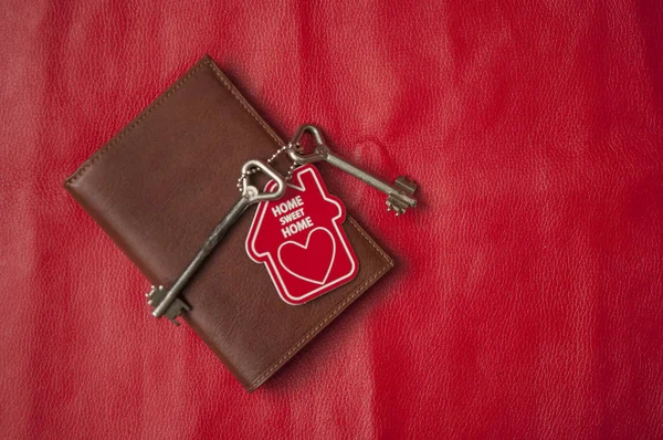 Brown leather wallet with home key on red background. Top view, — 스톡 사진