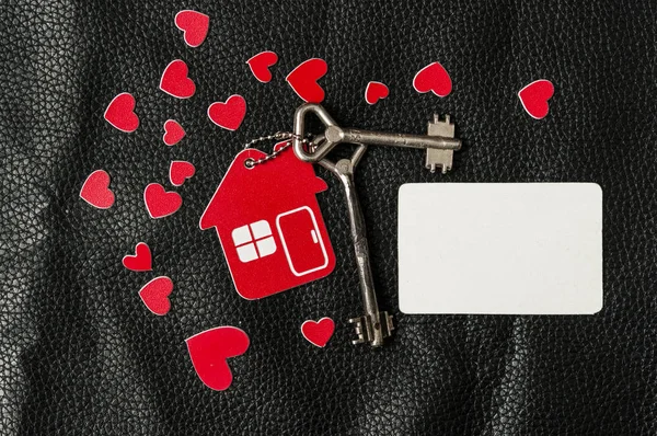 Casa pequena e uma chave com um chaveiro em forma de coração — Fotografia de Stock