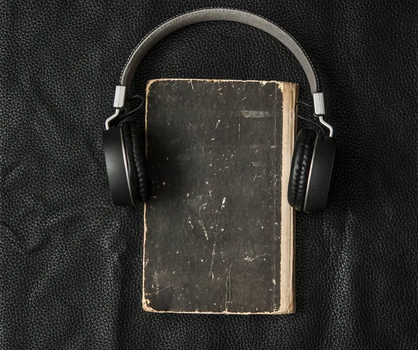 Primer plano del libro viejo con auriculares cubiertos de cuero negro ba — Foto de Stock