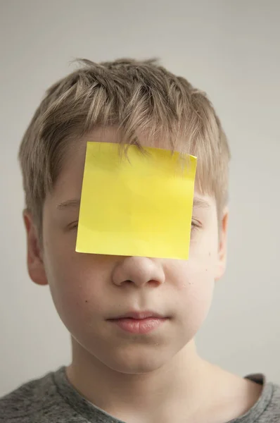 Gelangweilter und neugieriger kleiner Junge mit Notizzetteln auf der Stirn — Stockfoto