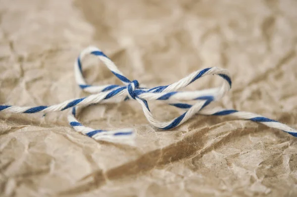 A rope tied with a bow on crumpled paper — Stock Photo, Image