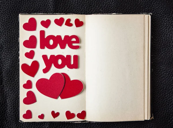 Livro antigo com uma forma de coração sobre fundo de couro preto — Fotografia de Stock