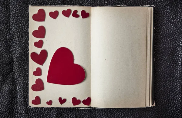 Старая книга с формой сердца на черном кожаном фоне — стоковое фото