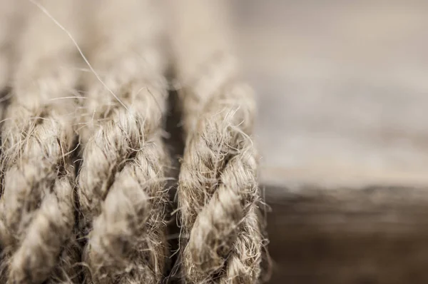 Close-up of a thick hemp rope. Natural rope on an old wooden table. Side view. Soft focus.