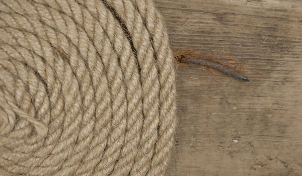 Close-up of a thick hemp rope. Natural rope on an old wooden table. Side view. Soft focus.