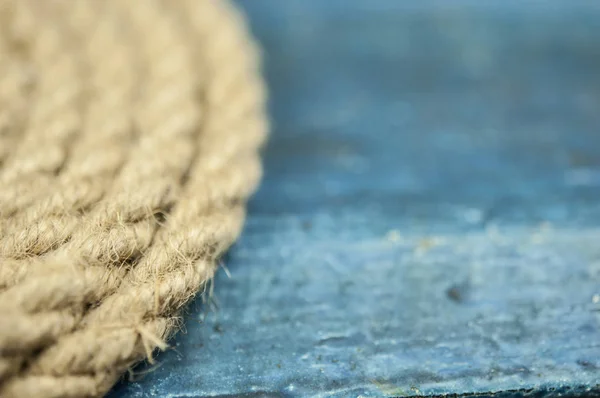 Close-up of a thick hemp rope. Natural rope on an old wooden table. Side view. Soft focus.