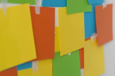 Beyaz bir duvarda bir sürü boş kare kağıt çıkartması var. Kapat.