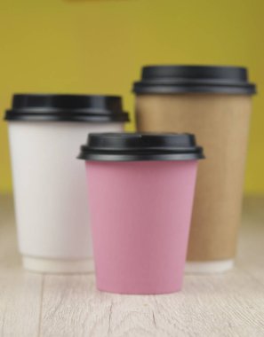 Tek kullanımlık renkli kağıt bardaklar ve ahşap masa kapakları.