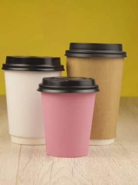 Tek kullanımlık renkli kağıt bardaklar ve ahşap masa kapakları.