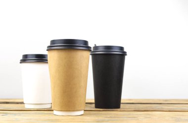 Tek kullanımlık renkli kağıt bardaklar ve ahşap masa kapakları.