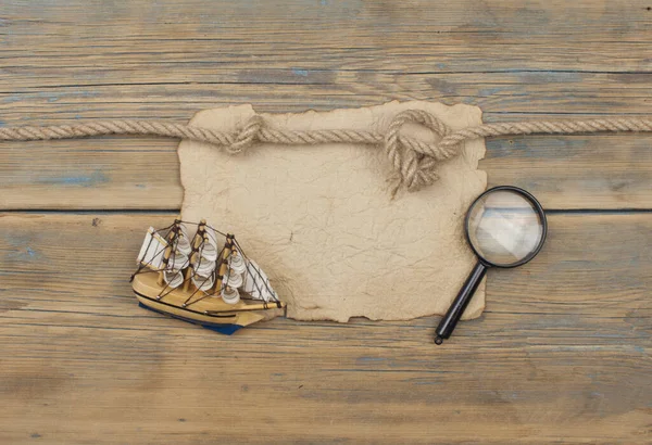 放大镜和木制背景古典船模型 — 图库照片