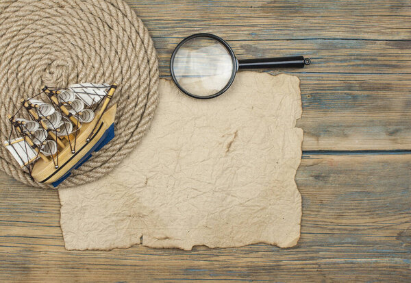 old paper, rope, magnifying glass and model classic boat on wood background   