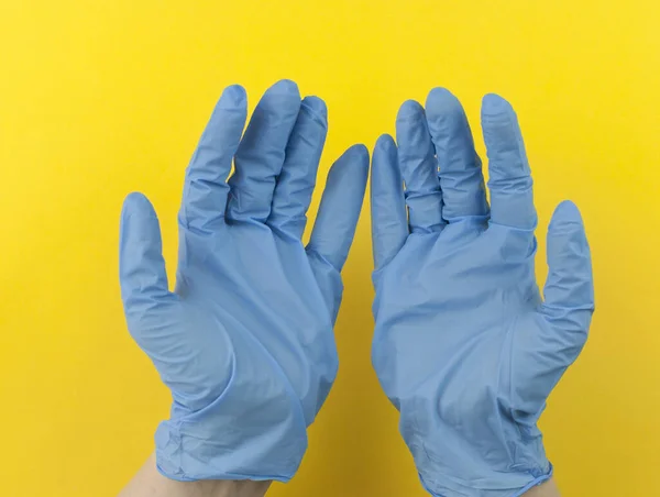 青い医療用手袋の2つの手は黄色の背景にオブジェクトを保持します モックアップ 広告のためにあなたの製品を挿入することができます 空の場所 — ストック写真