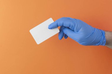 Steril lateks mavi eldivenli doktor boş bir beyaz kartvizit tutuyor, lenslerin yazılı olduğu şablonu, kapat.