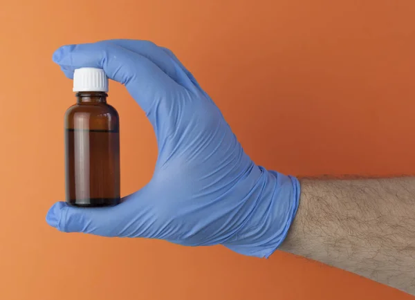 Kéz Kézben Kék Orvosi Kesztyű Tart Egy Sötét Üveg Gyógyszer — Stock Fotó