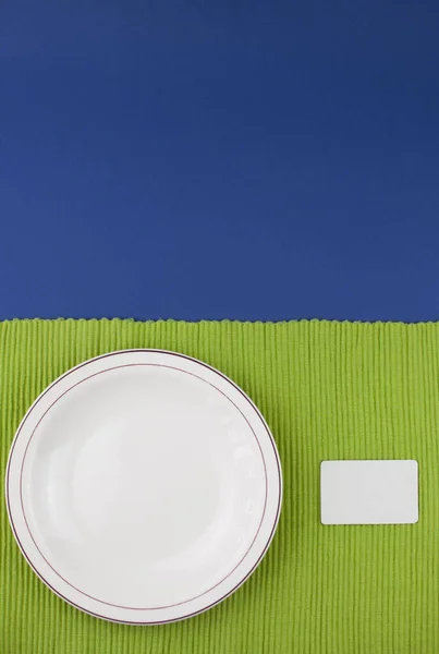 顶部视图 绿色桌布上贴有空标签的陶瓷盘 — 图库照片