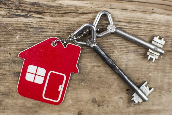 不動産 住宅や賃貸物件のための木製の床板の概念に休んで家の形のキーチェーン上の家の鍵 — ストック写真