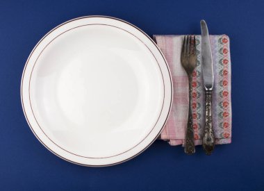 Boş tabak, çatal bıçak takımı ve havluyla mavi arka plan. Yukarıdan kopyalama alanı ile görüntüle