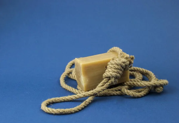 Rope with loop and brown soap on blue background. Rope with hangman\'s noose. Suicide concept