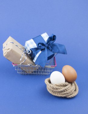 Metal sepet dolusu hediye kutusu ve mavi kağıtta iki Paskalya yumurtası.