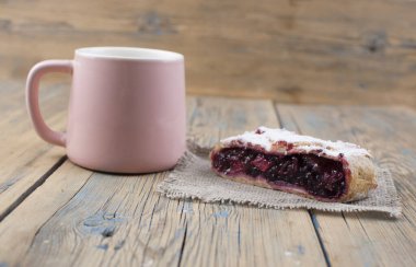 Ev yapımı çilekli turta. Kirazlı lezzetli Strudel. Turta, böğürtlenli turta ve ahşap masa zemininde bir fincan sıcak çay. Tatlı sağlıklı vejetaryen tatlı yemeği. 