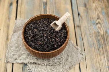 Bir sürü kuru siyah çay, ahşap kase ve ahşap kepçe.