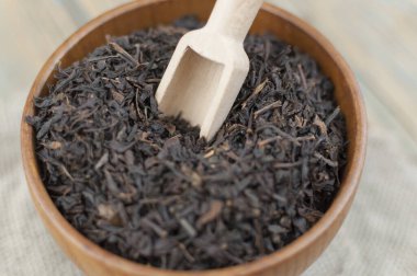 Bir sürü kuru siyah çay, ahşap kase ve ahşap kepçe.