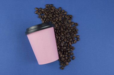 Kahve çekirdekli mavi arka planda plastik kapaklı pembe kağıt kahve fincanı. Kahve fincanı ve paket kahve. Kopyalama alanı, düz uzanma.