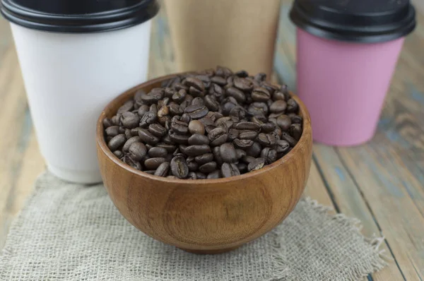 木製の背景に茶色のボウルに朝のエスプレッソとスプーンのためのコーヒー豆と使い捨てのテイクアウトモックアップ紙カップ — ストック写真