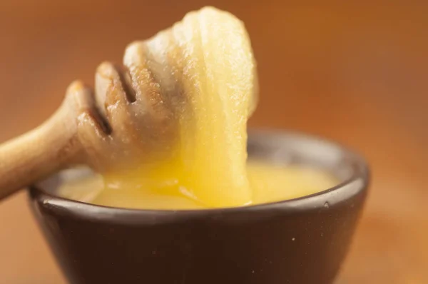 蜂蜜は粘土のボウルに蜂蜜のディップから滴り落ちる 接近中だ 健康的な有機厚さの蜂蜜は 木製の蜂蜜のスプーンから浸漬 閉じます 甘いデザートの背景 — ストック写真