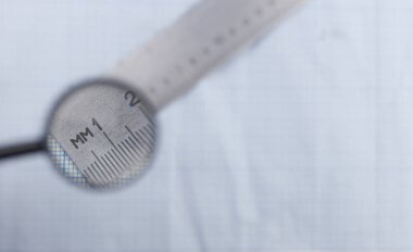 Büyüteçle grafiksel arkaplan üzerinde makro metal cetvel