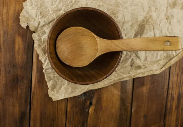 Wooden empty bowl and spoon hand on the dark wooden table. The view from the top. Flat lay.