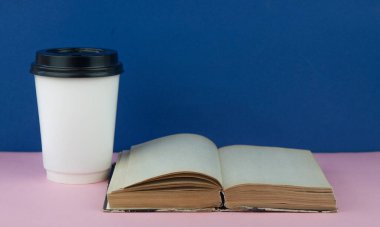 Kahve fincanı bir yığın kitabın üzerinde duruyor. Kahve molası, kahve ve kitap konsepti..