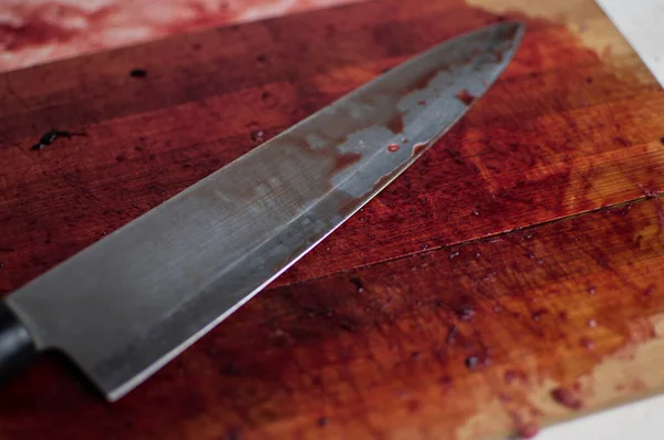 knife with grunge of blood on wood cutting board