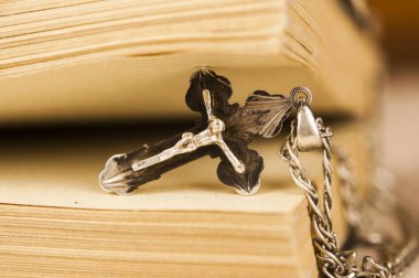 Gümüş zincirli, ahşap arka planlı, boş bir kitapla Hıristiyan haçı kapatıldı.