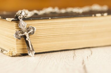 Gümüş zincirli, ahşap arka planlı, boş bir kitapla Hıristiyan haçı kapatıldı.