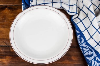 Kahverengi ahşap masaya peçeteli boş tabak.