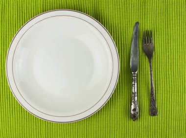 Tahta arka planda çatal bıçak takımı olan beyaz tabak.