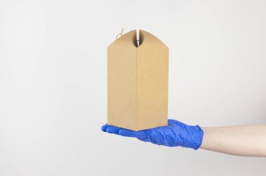 Mavi, tek kullanımlık bir eldivende beyaz arka planda bir fiyonk olan hediye kutusu bulunur.