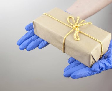 Mavi, tek kullanımlık bir eldivende beyaz arka planda bir fiyonk olan hediye kutusu bulunur.