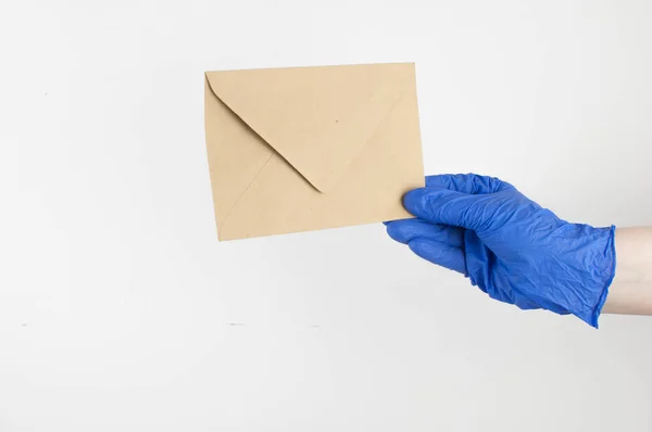 青い医療用手袋の手は白い背景に封筒を持ってる 検疫コロナウイルスパンデミックにおける非接触配送サービス — ストック写真