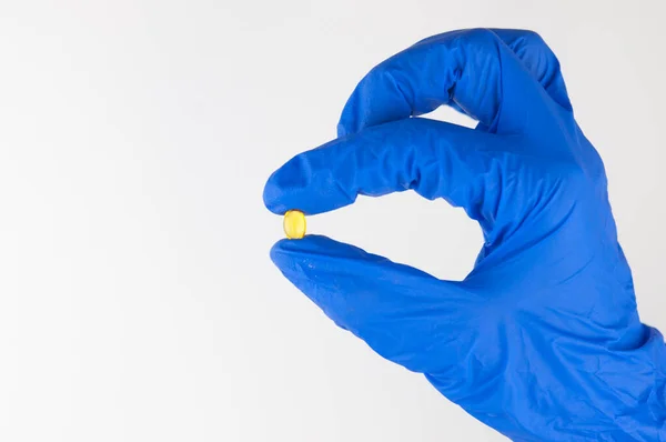 Hrst Žlutých Průhledných Pilulek Mezi Dvěma Prsty Ruce Gumové Modré — Stock fotografie