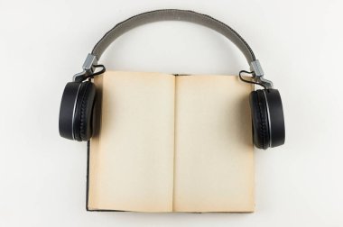 Ses kitabı konsepti. Beyaz arka planda kitap olan kulaklıklar. Kitap dinliyordum. Modern eğitim.