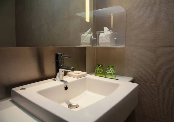 Grifo de agua y fregadero blanco de cerámica en un WC moderno con azulejos marrones —  Fotos de Stock