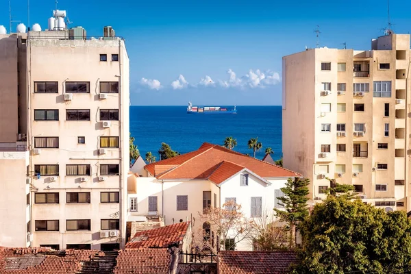 As águas azuis brilhantes do mar Mediterrâneo através de edifícios residenciais. Limassol, Chipre . — Fotografia de Stock