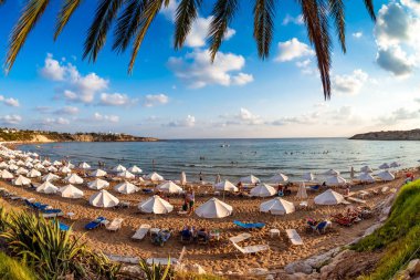 Tourists relaxing on the beach in the summer vacation. Peyia village, Paphos District, Cyprus. clipart
