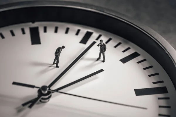 Dos hombres de negocios parados en medio de la esfera del reloj. Concepto empresarial . — Foto de Stock