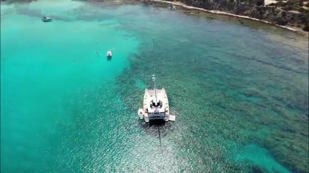 在蓝绿色海水中锚定的双体船周围飞行 — 图库视频影像