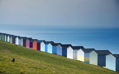 Blue sky and colorful beach huts along the coastline of Whitstab clipart