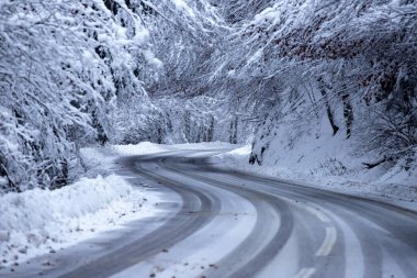 Kenarlarında kar yığınları olan boş yol.